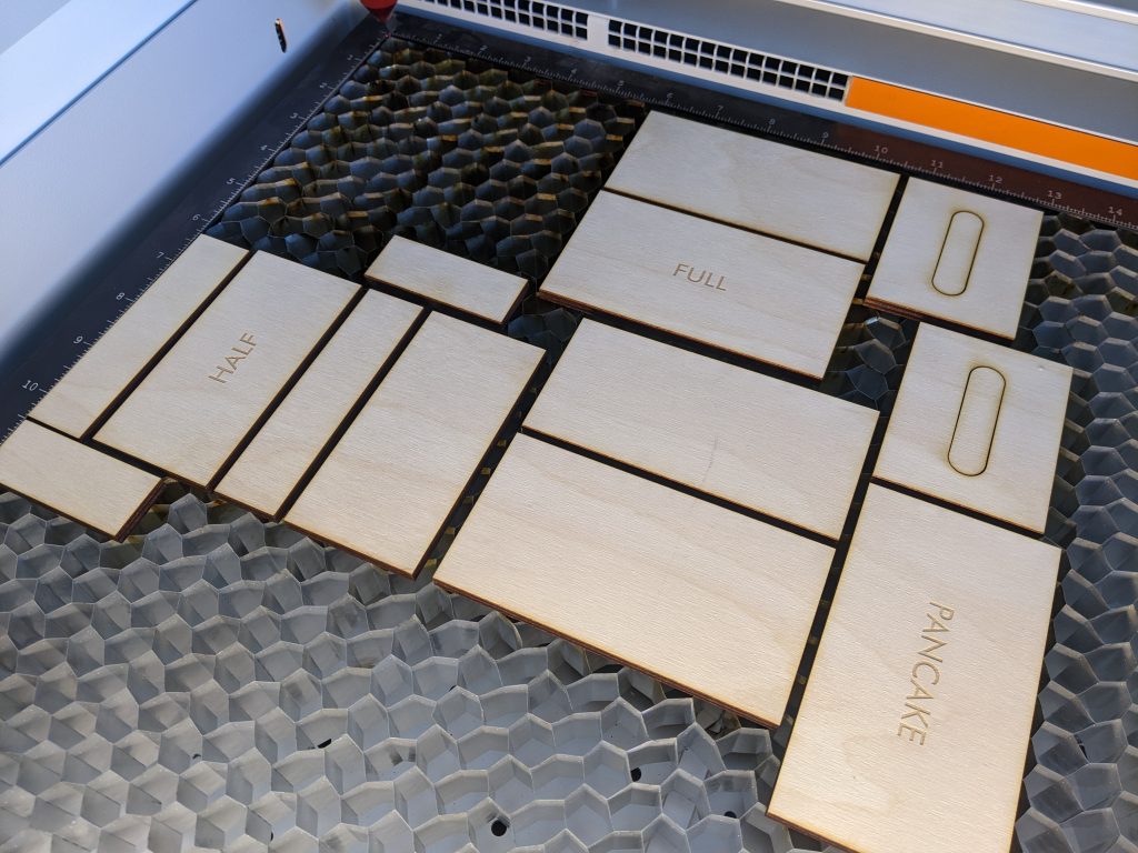 Laser cut and laser engraved plywood pieces on laser cutting vector grid.